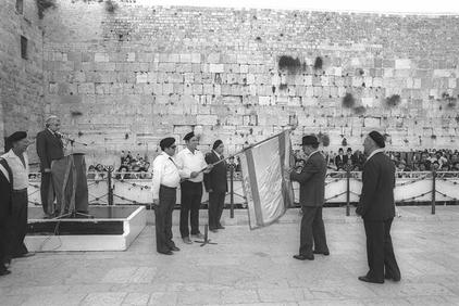 Begin affixes the ribbon to Etzel flag